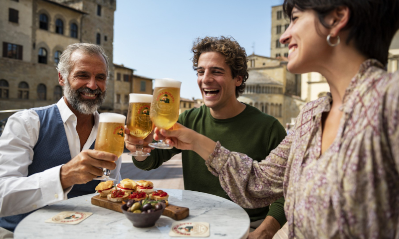 Drie mensen proosten met Birra Moretti op een terras in Italië